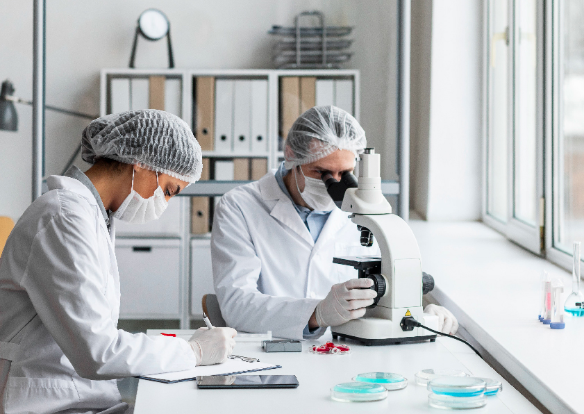 Two scientists in lab coats examining a microscope at Rushabh Pathology Laboratory.